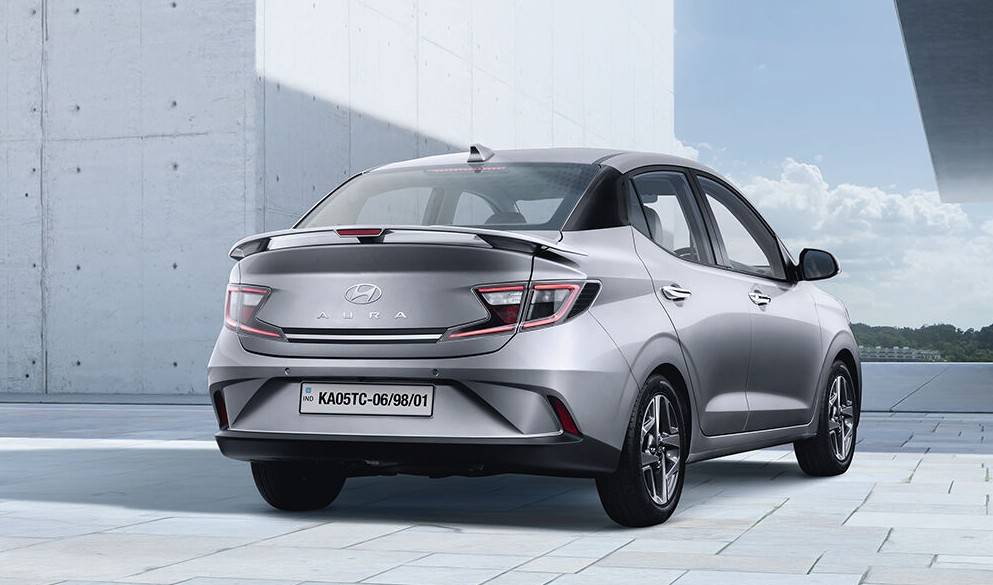 Hyundai AURA 2025 rear view showcasing LED tail lamps, spoiler and bold bumper design in silver color
